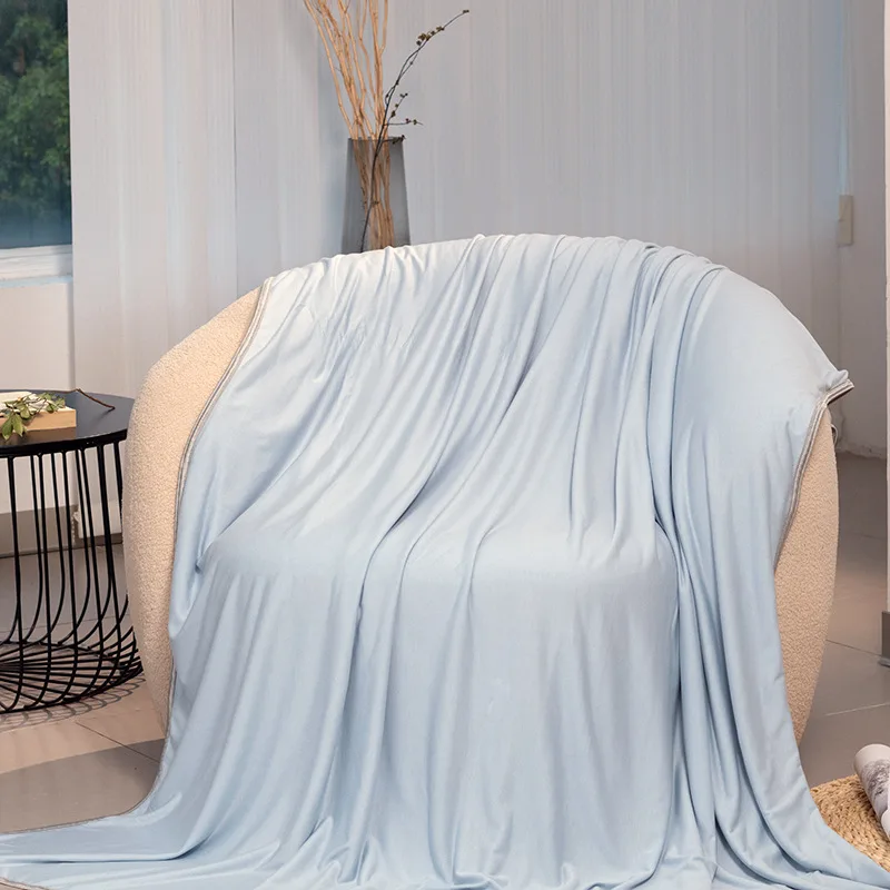 Couverture fraîche bleue en fibre de bambou posée sur un fauteuil