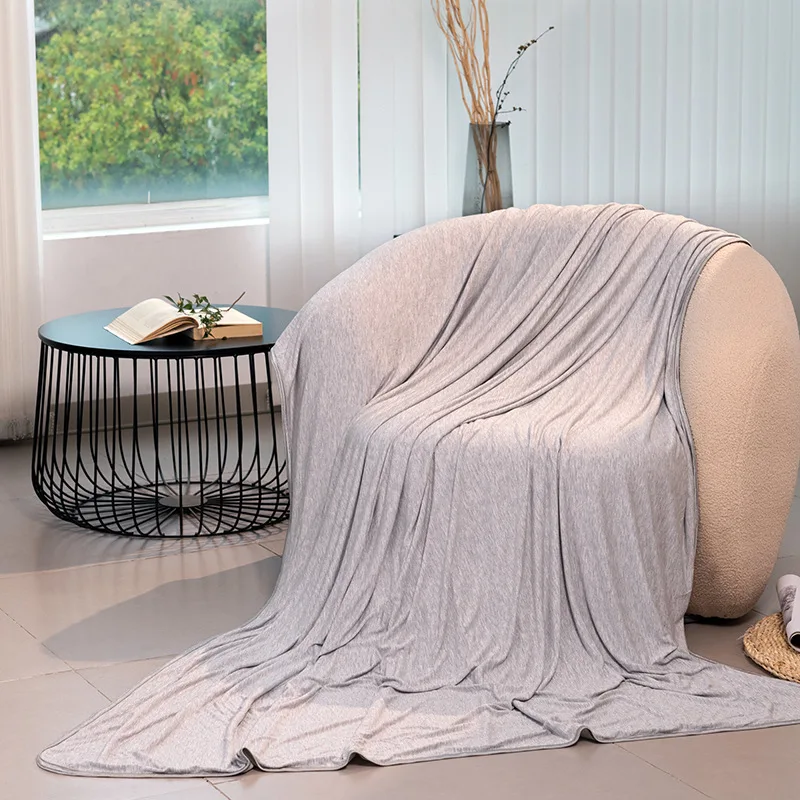 Couverture fraîche grise en fibre de bambou posée sur un fauteuil
