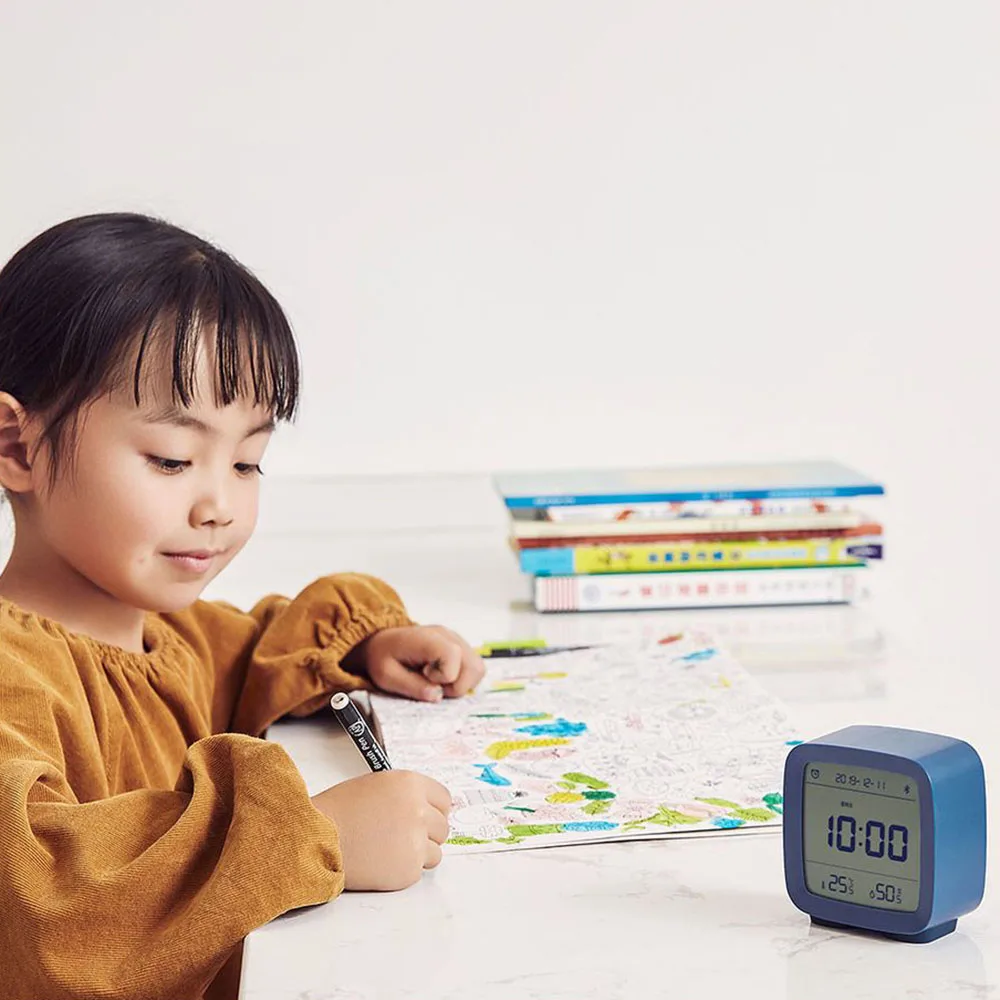 Réveil thermo-hygromètre posé sur le bureau d’un enfant qui dessine