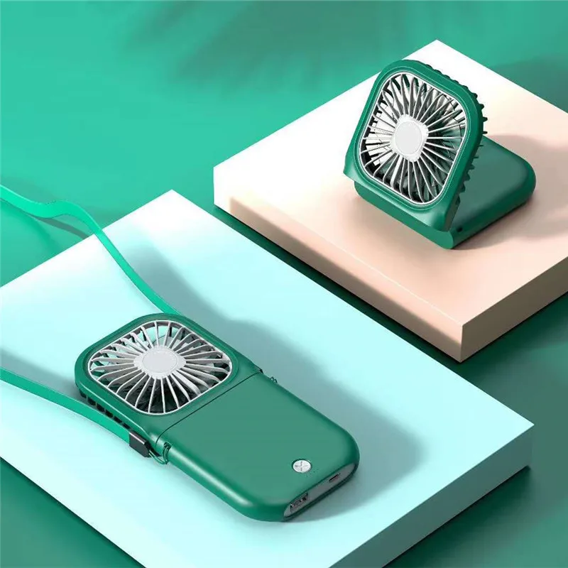 Ventilateur pliant vert posé et un second porté au cordon, mise en scène