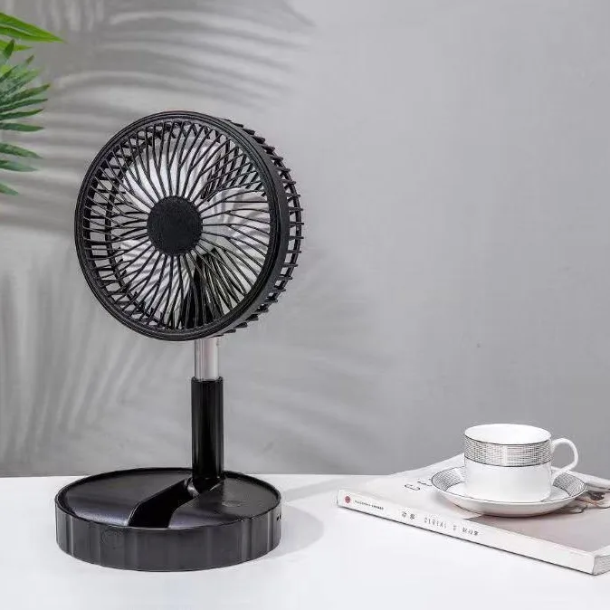 Ventilateur télescopique noir posé sur une table à côté d’une tasse