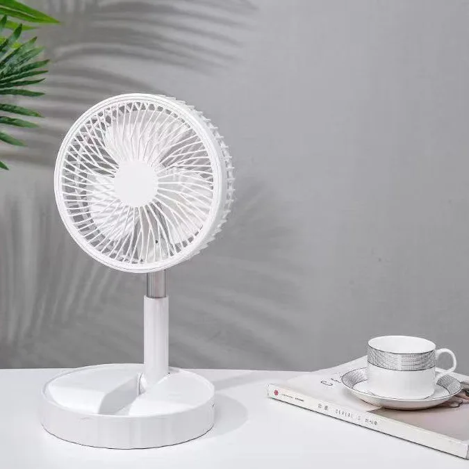 Ventilateur télescopique blanc posé sur une table à côté d’une tasse